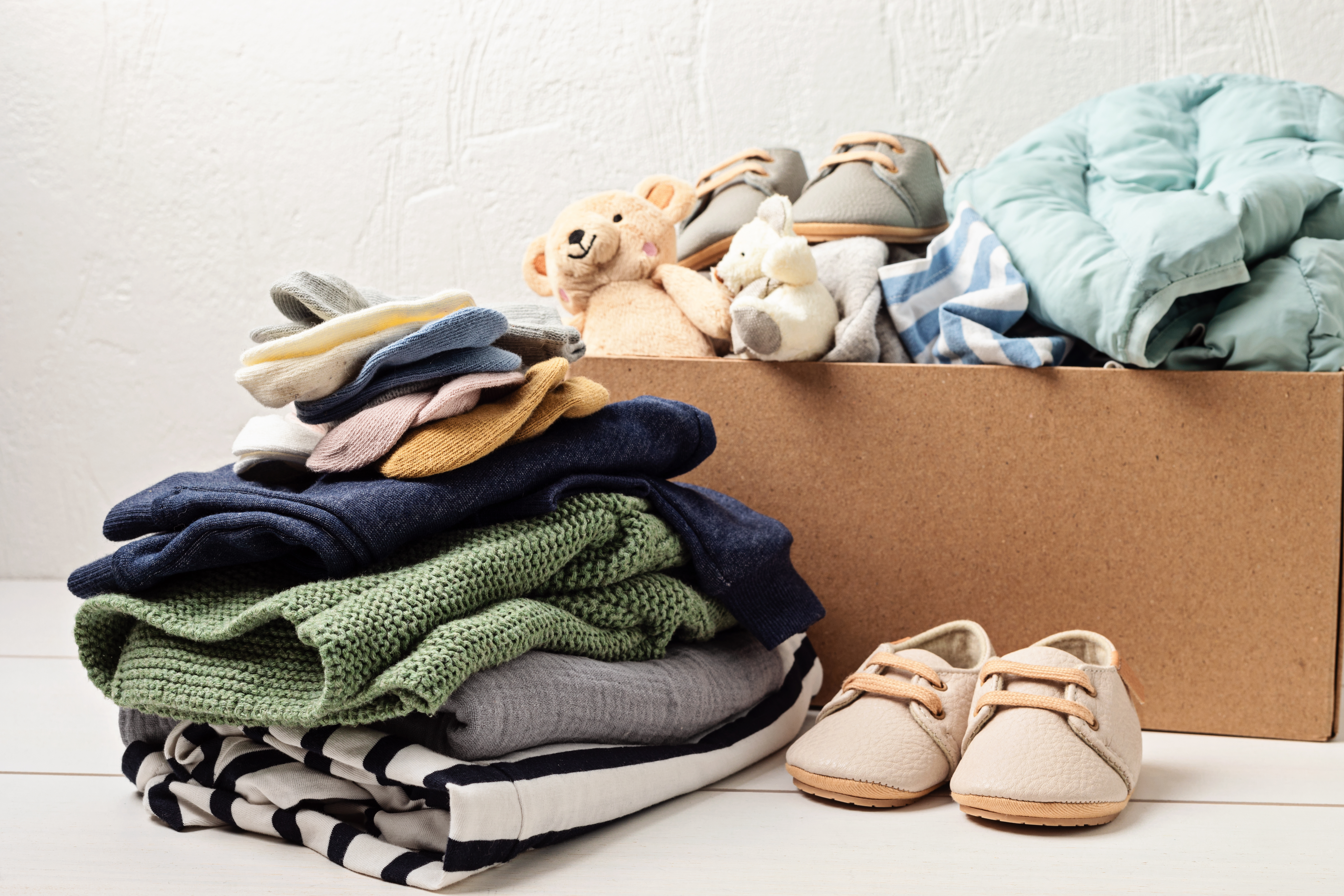 Baby and child clothes, toys in box. Second hand apparel idea